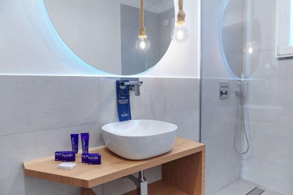 A modern bathroom with a round mirror, a white sink, and a handheld showerhead.