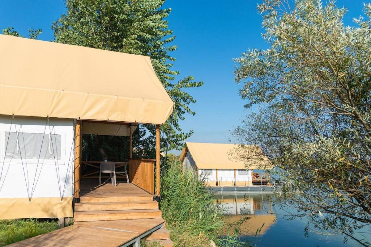 Un chalet au bord du lac, doté d’une terrasse en bois et d’un espace salon extérieur abrité.