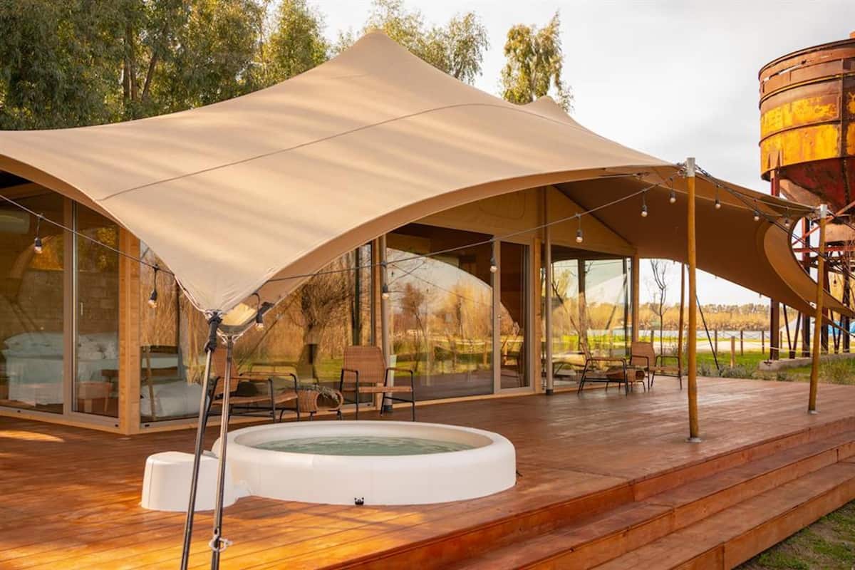 Un espace de détente extérieur moderne, doté d’un grand auvent, d’un jacuzzi et d’une terrasse en bois.