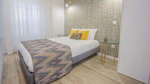 Un dormitorio moderno con una cama, un edredón estampado y un diseño geométrico en la pared.