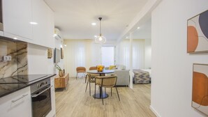 Una cocina moderna con encimera de mármol, horno empotrado y comedor con mesa y sillas redondas.
