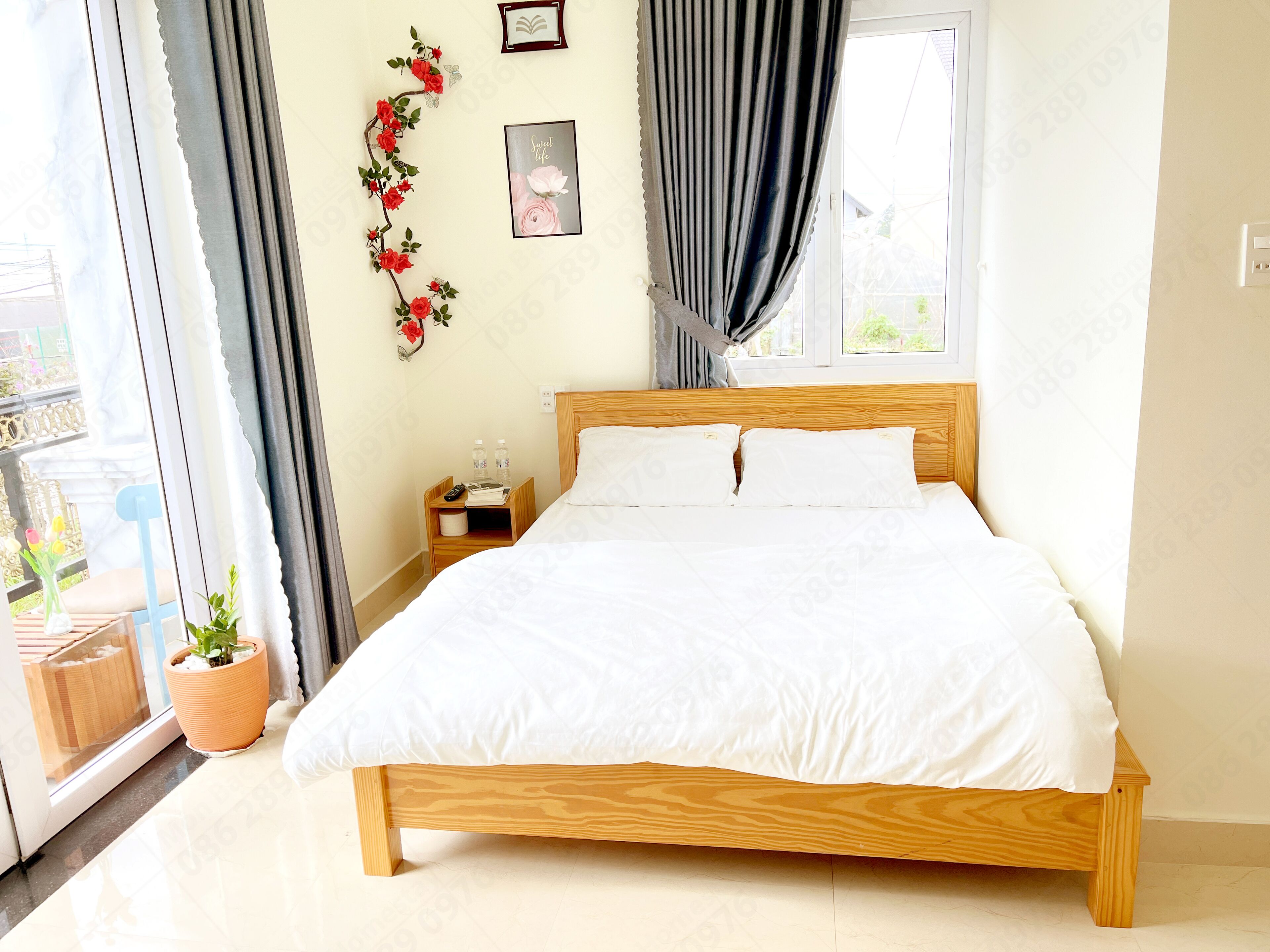 A neatly made bed with white linens, a wooden headboard, and a nightstand with a remote control and books beside it.