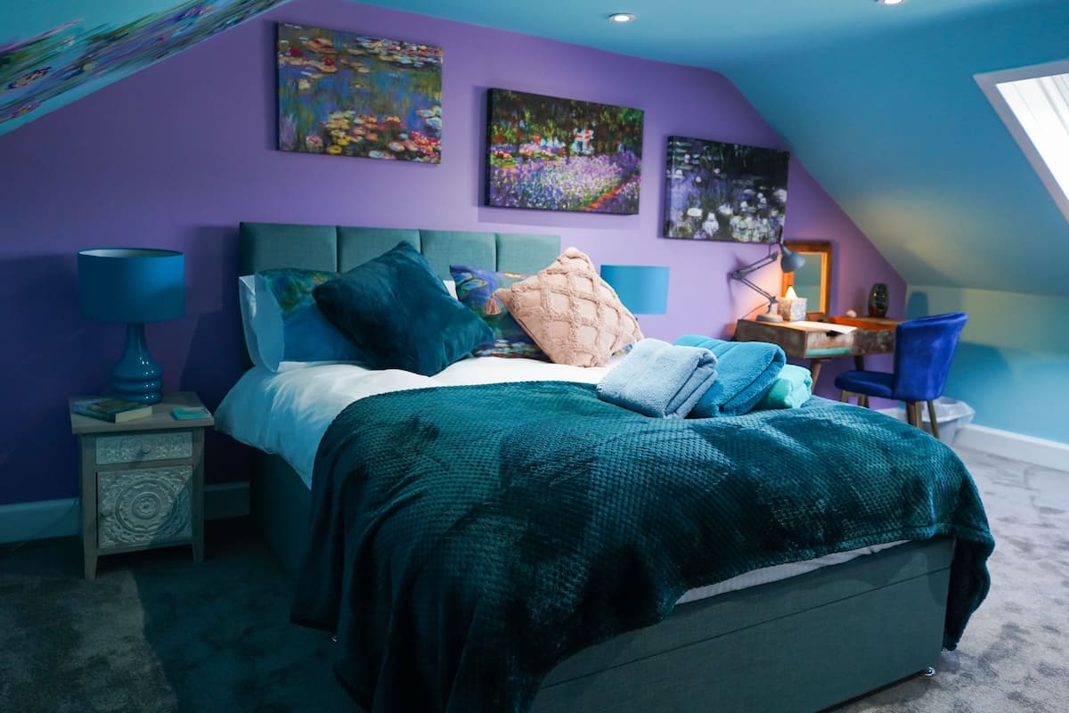 A bedroom with a bed, nightstands, a desk, and a chair.