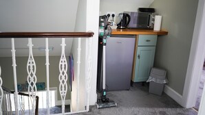 A compact kitchen with a refrigerator, microwave, and coffee maker on a countertop. - The Art Bank (Dalbeattie)