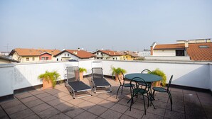 A rooftop terrace with lounge chairs, a table, and potted plants. - La terrazza di Giulietta (San Giovanni Lupatoto)