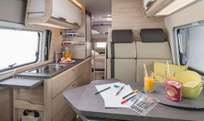 Enjoy a compact and functional living space with a kitchenette, dining area, and comfortable seating for two.