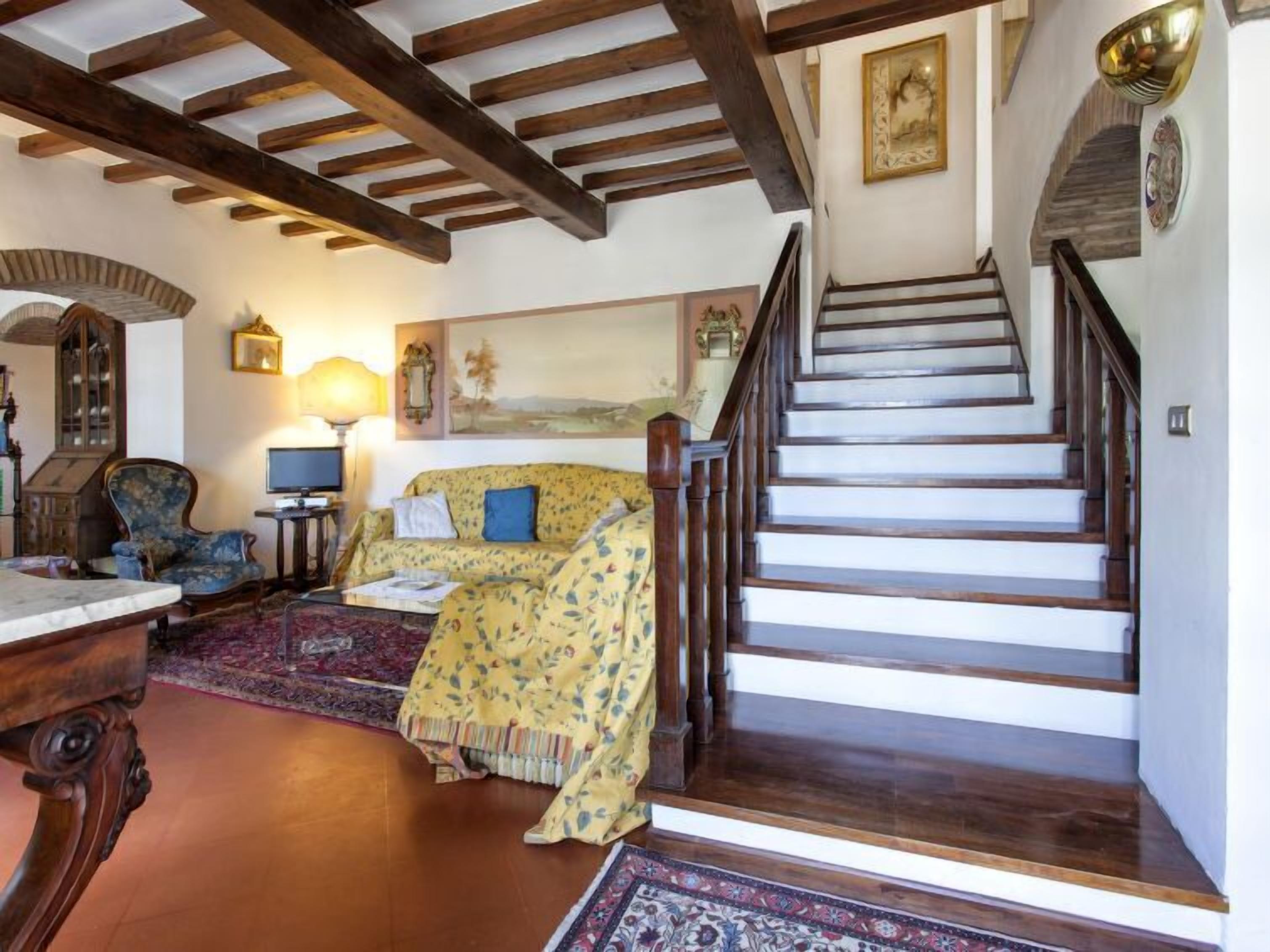 A traditional interior with a wooden staircase, a sofa, a lamp, and a cabinet.