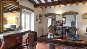 A traditional room with exposed wooden beams, a large ornate mirror, a wooden desk with a bowl, and a bookshelf. - Vacation home Virgo by Interhome (Cortona)