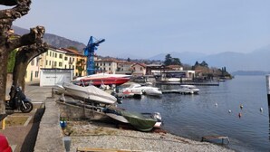 A marina with boats docked, a crane, and buildings along the waterfront. - La tana del pescatore by Interhome (Tremezzina)