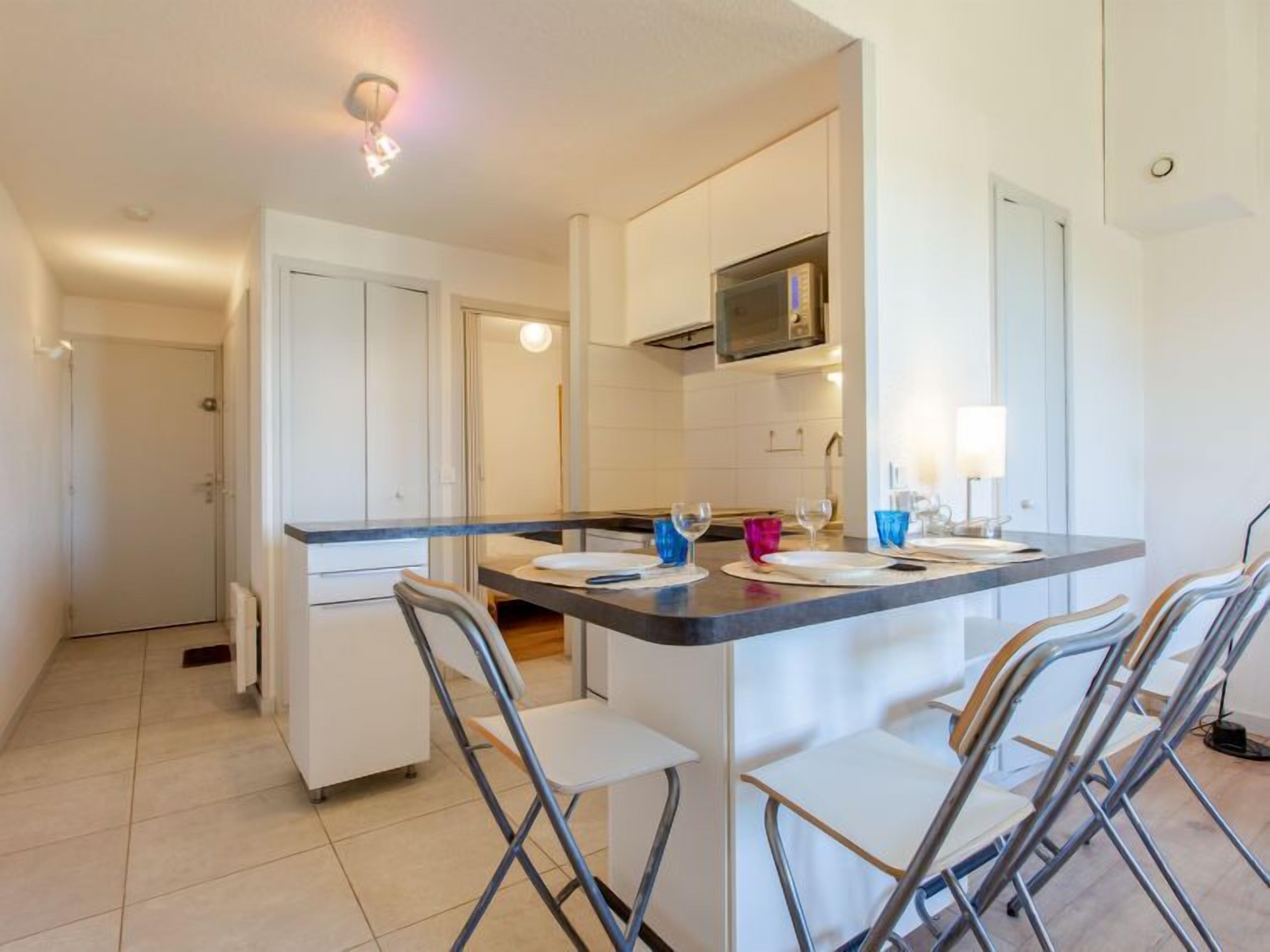 A modern kitchen with a central island, white cabinets, and a microwave above the counter.