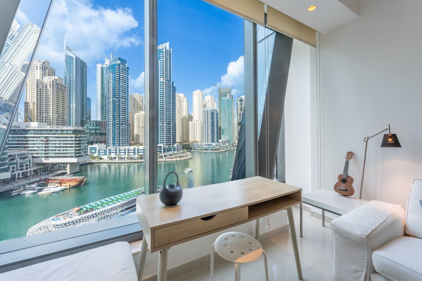 Ein modernes Hotelzimmer mit großem Fenster und Blick auf eine Stadtlandschaft sowie einen Hafen.