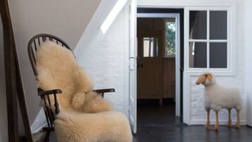 A room with a rocking chair, a fluffy rug, and a wooden sheep figure.