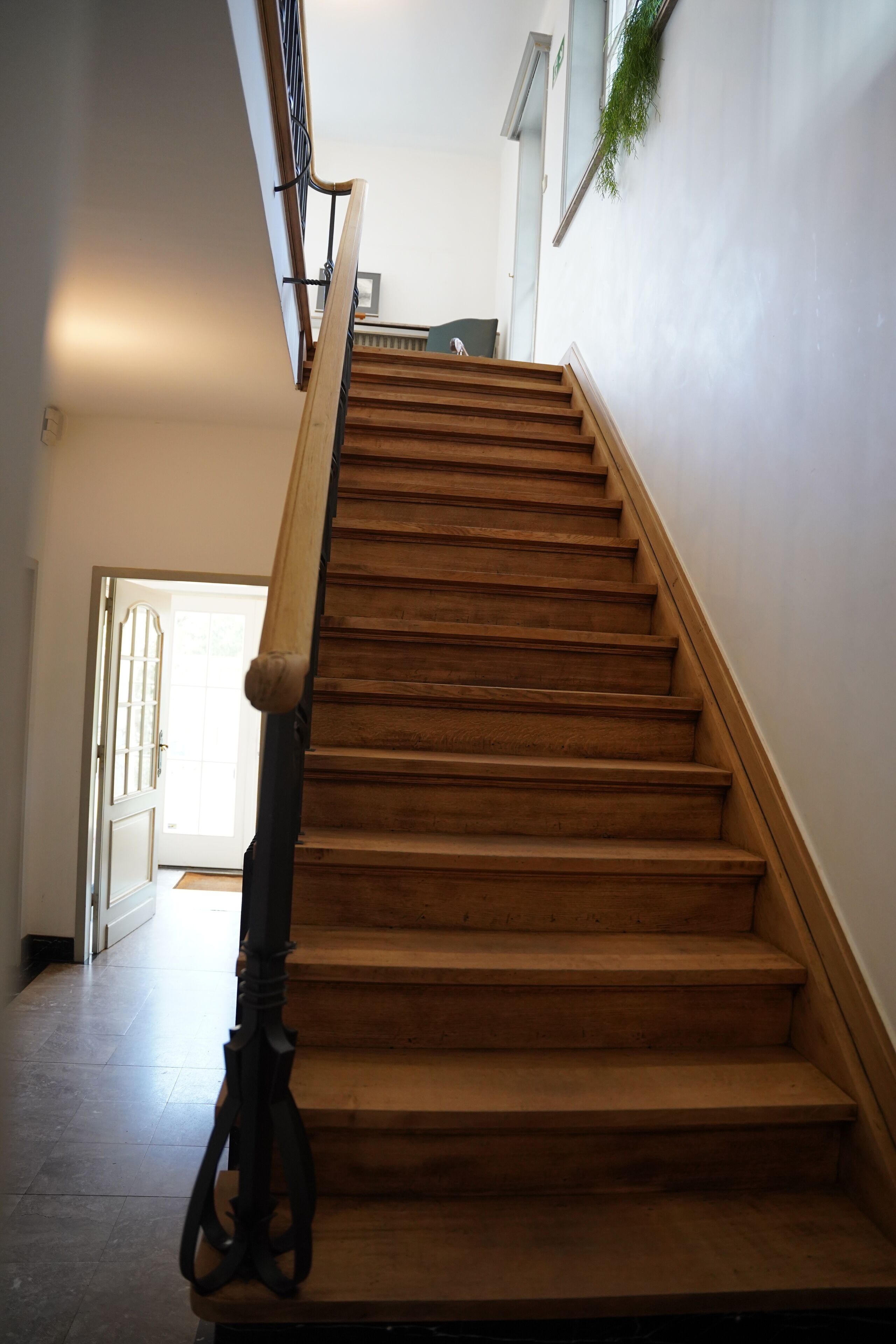 A wooden staircase with a handrail, leading to an upper floor.