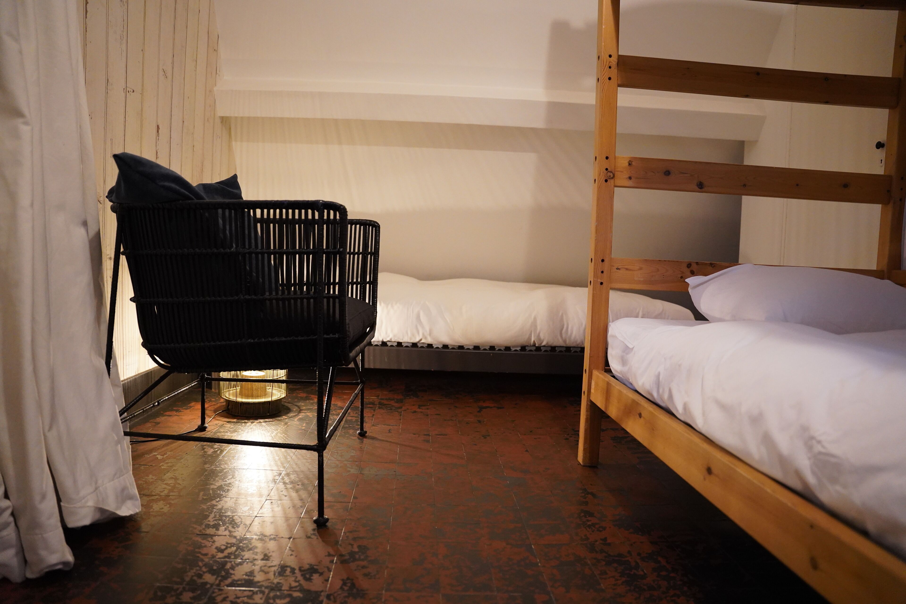 A bunk bed room with a black chair and a small table.
