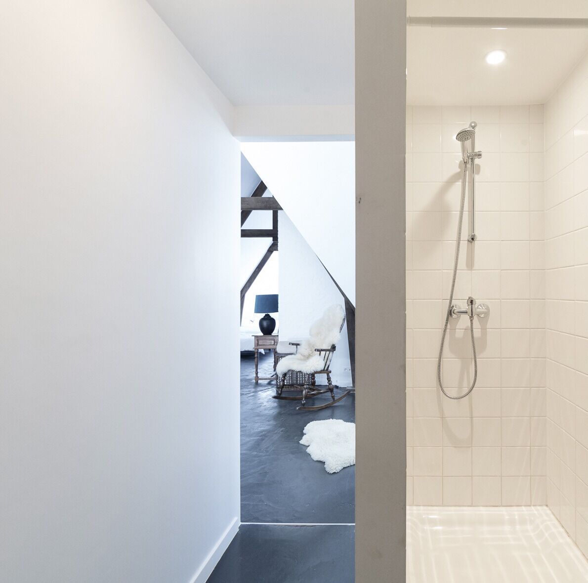 Une salle de bain moderne avec une douche, un tapis blanc et moelleux et une chaise placée dans un coin.