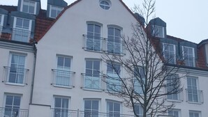 Un edificio con el letrero "Olymp" en la entrada, de estilo arquitectónico moderno con varias ventanas y balcones.