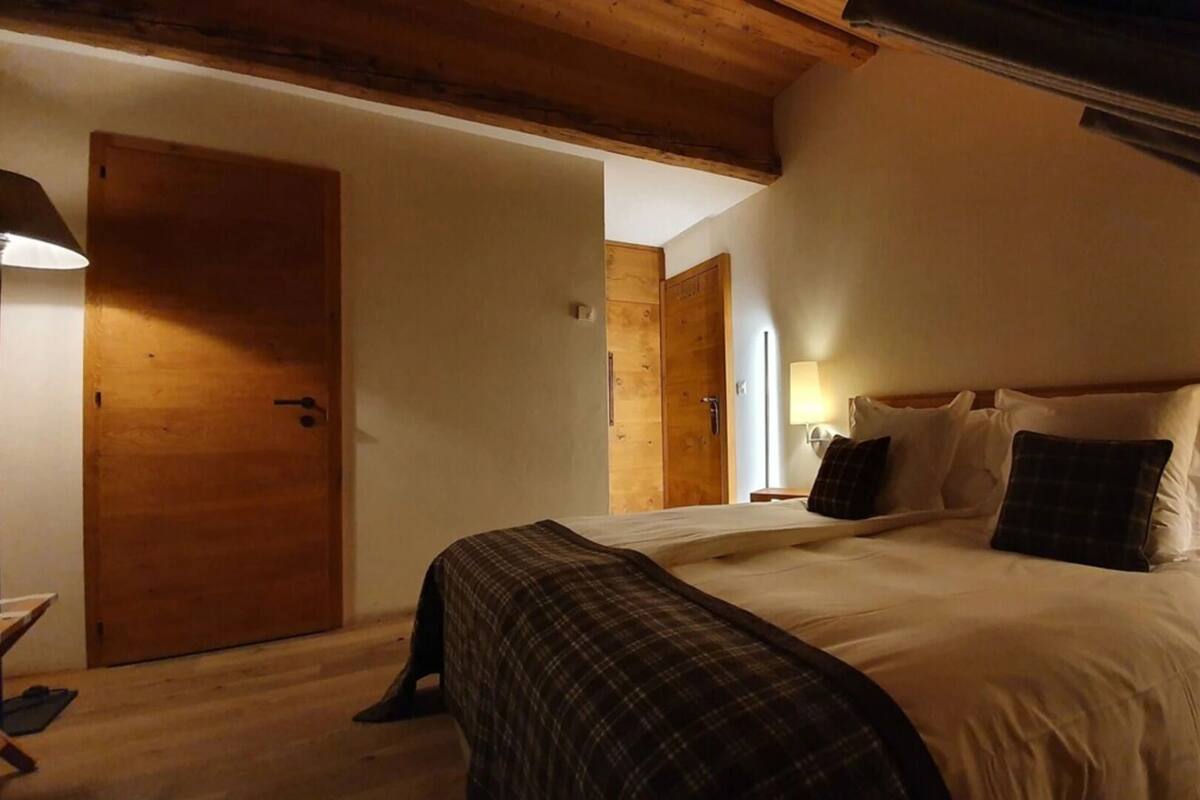 Ein Schlafzimmer mit einem großen Bett, einer Holztür und einer Lampe.