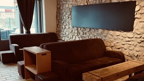 A cozy living area with a stone wall, a large flat-screen TV, and a wooden coffee table. - Auberge de l'Union Arzier (Arzier)