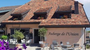 A building with a tiled roof, outdoor seating, and a sign reading "Auberge de l'Union". - Auberge de l'Union Arzier (Arzier)
