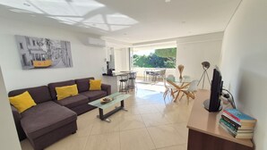 Een moderne woonkamer met een bank, salontafel en een eethoek met stoelen en een tafel.