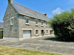Un bâtiment en pierre avec un toit en pente, de nombreuses fenêtres et un garage.