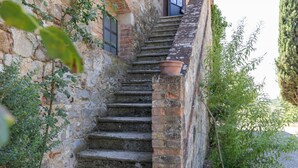 Eine Steintreppe führt zu einem Gebäude mit einem Ziegelunterbau, umgeben von Grünpflanzen.