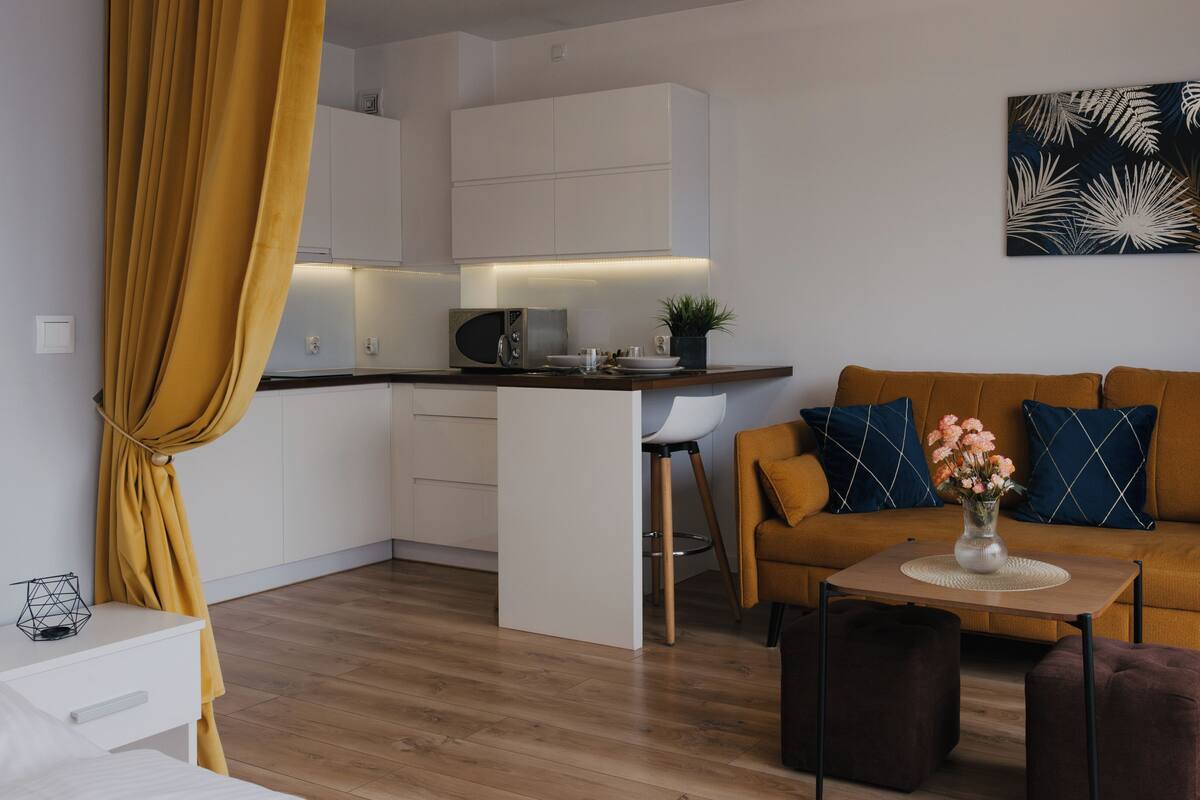 Una sala de estar moderna con un sofá, una mesita de centro y una cocina con microondas.