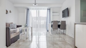 Una sala de estar moderna y bien iluminada con un sofá, una mesa de comedor y sillas.