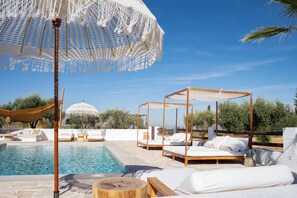 A poolside area with a wooden bed, lounge chairs, and a white canopy umbrella. - Finca las Calmas (Salar)