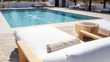 Una piscina al aire libre, tumbonas