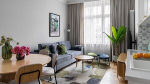 Una sala moderna con un sofá gris, una mesa de comedor de madera y una planta grande.