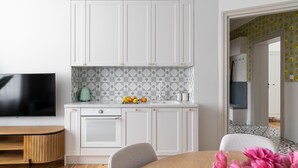 Una cocina moderna con armarios blancos, horno empotrado y una encimera con frutas.
