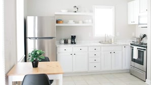 Eine moderne Küche mit weißen Schränken, einem Edelstahlkühlschrank, einer Spüle und einem Backofen.