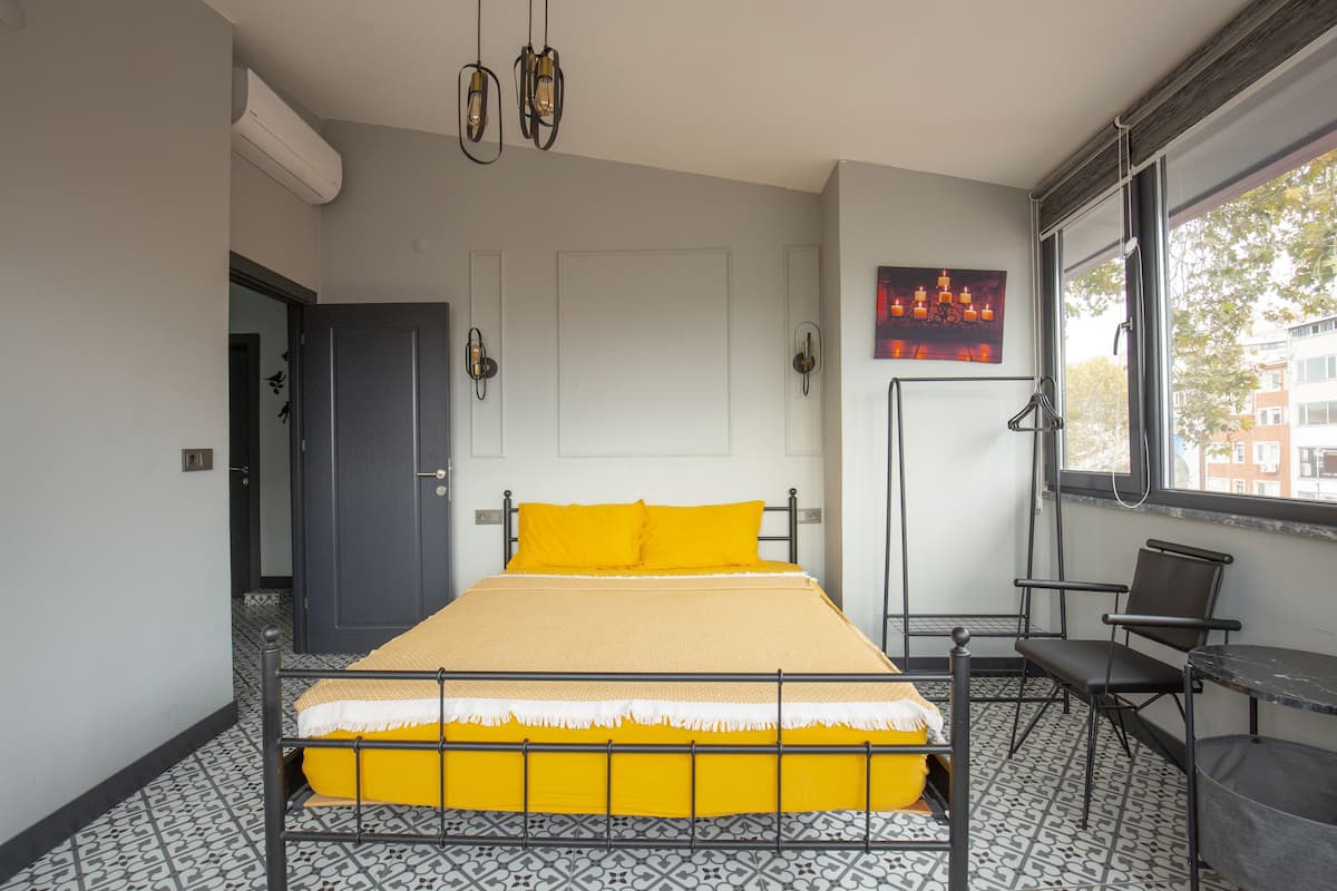 A room with a bed, a chair, a table, and a window.
