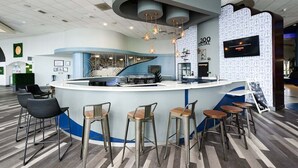 Un área de bar moderna con una barra curva, varios taburetes y lámparas colgantes.