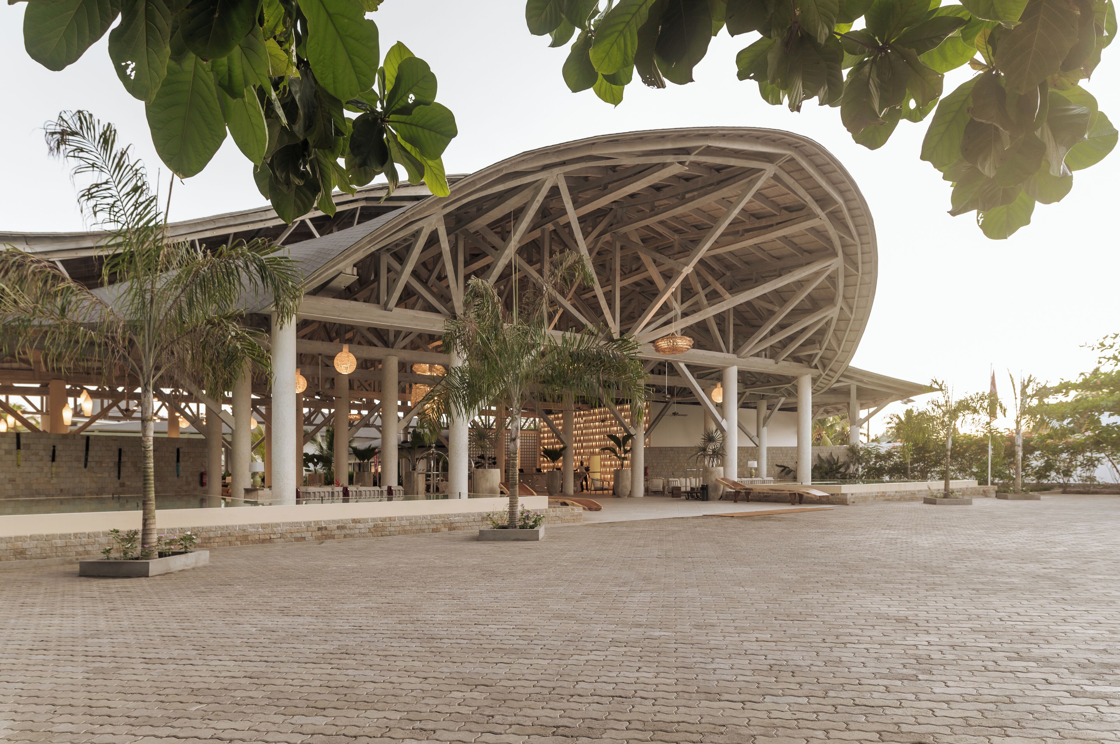 Un edificio moderno con una amplia estructura de techo curva y una plaza pavimentada al frente.