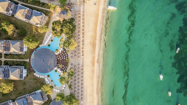 Vista aérea de un complejo turístico con piscina, playa y barcos.