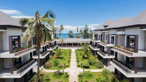 Un resort con edificios de varios pisos, un patio central con senderos y palmeras.