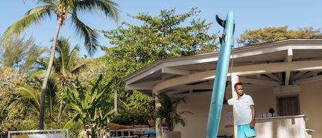 A man standing next to a blue surfboard in front of a building labeled "NAUTICAL POINT".
