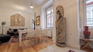 Ein modernes Wohnzimmer mit Essbereich, einer großen Skulptur und Kunstwerken an den Wänden.