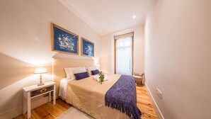 A bedroom with a bed, nightstand, lamp, and two framed pictures on the wall. - Central 2BR/2BA Apartment Balcony Elevator in Baixa (Lisboa ciudad)