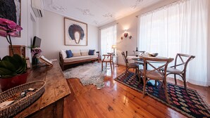 A living room with a wooden floor, a sofa with cushions, a dining table with chairs, and a zebra rug. - Baixa Apartment 2BR|2BA with Balcony, Lift (Lisboa ciudad)
