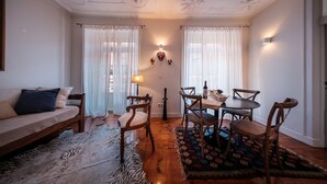 A cozy living room with a sofa, wooden chairs, a dining table, and a zebra-patterned rug. - Baixa Apartment 2BR|2BA with Balcony, Lift (Lisboa ciudad)