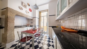 A kitchen with a checkered floor, a dining table with chairs, a hanging light, and a window with a view. - Family Friendly 3BR/2BA Central Apartment in Baixa (Lisboa ciudad)