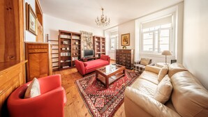 A living room with a red sofa, a beige sofa, a coffee table, and a bookshelf. - Family Friendly 3BR/2BA Central Apartment in Baixa (Lisboa ciudad)