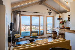 A living room with a sofa, two chairs, a TV, and a view of the city through large windows. - Apartment of stars 2BR/2BR with River & Town View (Lisboa ciudad)