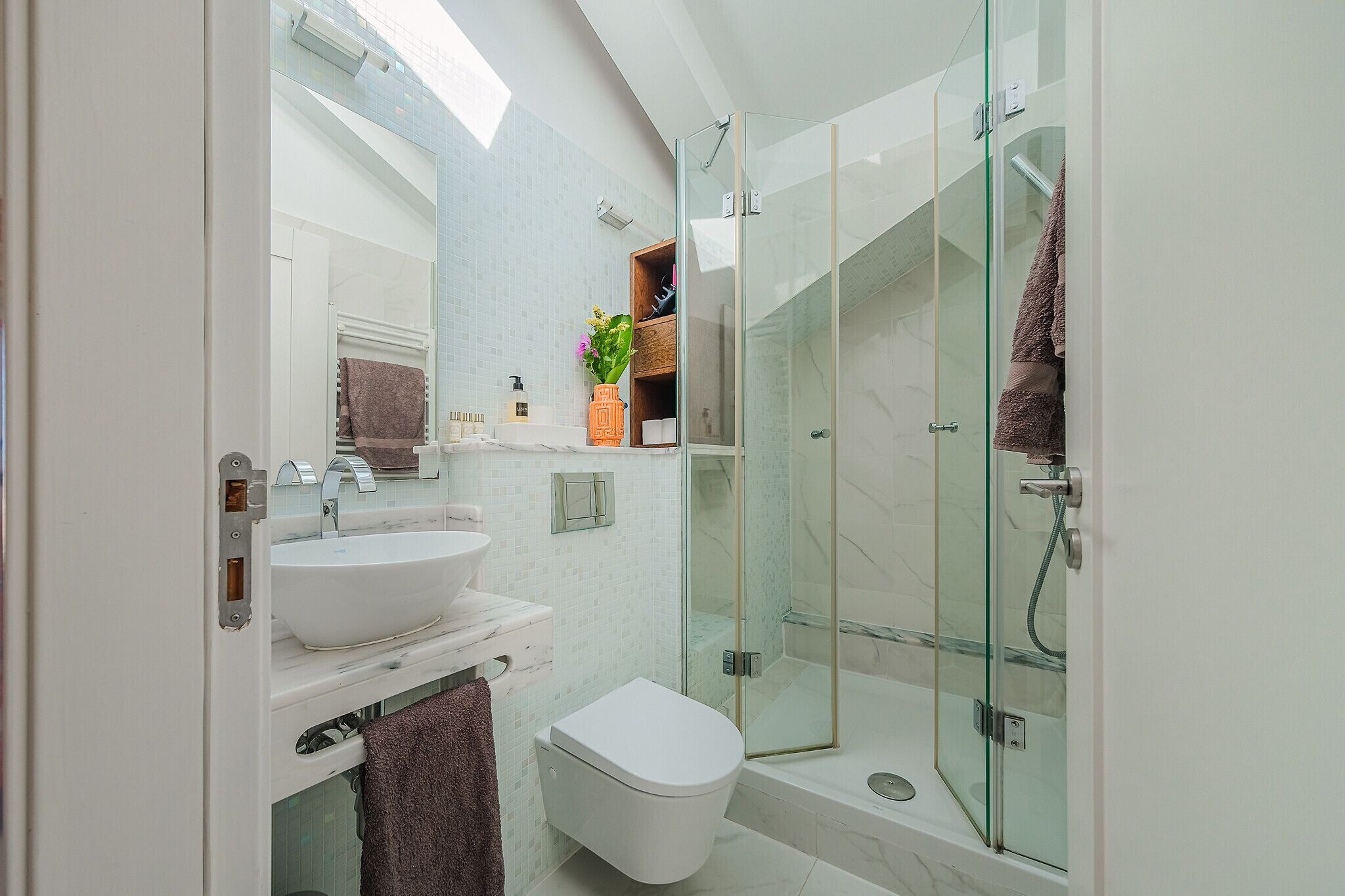 Ein modernes Badezimmer mit einer Duschkabine aus Glas, einem weißen Waschbecken und einer Toilette.
