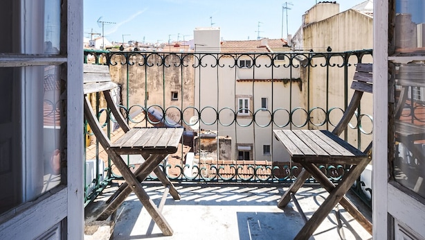 Ein Balkon mit Blick auf Gebäude, einem Holztisch und einem Metallgeländer.