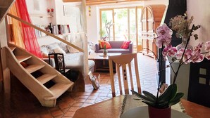 A spacious living area with a wooden staircase, a sofa, a coffee table, and a potted orchid.