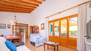 A spacious living area with a wooden ceiling, a dining table, a sofa with cushions, and a glass coffee table. - ES MUSSOL - Villa with private pool in SA POBLA. Free WiFi (Sa Pobla)
